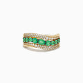 The 14K Yellow Gold Emerald and Diamond Wave Band features a central row of green emeralds bordered by two wavy rows of sparkling white diamonds in an elegant overlapping design.
