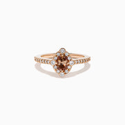 The 14K Rose Gold Brown and White Diamond Halo Ring showcases an oval brown and white diamond center, encircled by a halo of white diamonds and set with additional diamonds along the band.