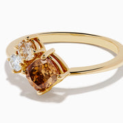 The Espresso 14K Yellow Gold Brown and White Diamond Ring showcases a round white diamond, a pear-shaped light brown diamond, and a cushion-cut brown diamond in a minimalist design against a white background.