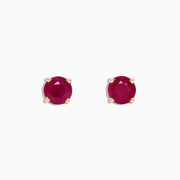 The Ruby Royale 14K Yellow Gold Round Solitaire Ruby Stud Earrings (1.14 TCW) feature faceted rubies in classic four-prong yellow gold settings, showcased on a plain white background.