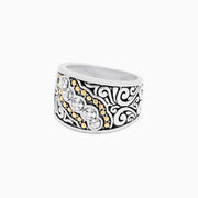 The 925 Sterling Silver and 18K Yellow Gold Diamond Ring, 0.10 TCW features a wide band with black swirls, a central row of sparkling diamonds, and small 18K yellow gold accents.