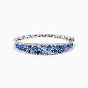 The 14K White Gold Natural Blue Sapphire & Diamond Bangle (7.82 TCW) features an intricate lattice design with clusters of round blue sapphires and sparkling diamonds along the front.