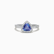 The Nahla Siri 14K White Gold Trillion Tanzanite and Diamond Ring, 0.96 TCW, showcases a triangular blue tanzanite center with a halo and band of sparkling white diamonds, presented on a white background.