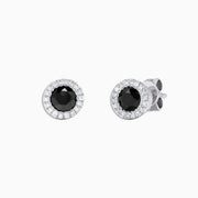 These 14K white gold stud earrings showcase a central black diamond surrounded by a halo of white diamonds, totaling 0.91 TCW for a timeless black and white design. Product: 14K White Gold Black and White Diamond Stud Earrings, 0.91 TCW.