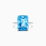 The Ocean Bleu 14K White Gold Blue Topaz and Diamond Ring, 8.06 TCW, showcases a large rectangular blue topaz center with sparkling diamonds along the band, displayed on a plain white background.