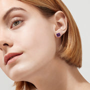 A pair of 14K Yellow Gold Amethyst Stud Earrings, 4.25 TCW, with cushion-cut gems set in prongs, displayed against a plain white background.