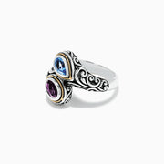 The 925 Sterling Silver & 18K Gold Topaz and Amethyst Ring, 1.62 TCW, features ornate patterns and two teardrop gemstones—blue topaz and purple amethyst—set side by side in gold-edged bezels on a white background.