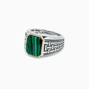 The Mens Sterling Silver and 14K Yellow Gold Malachite Ring, 6.05 TCW, features an intricate geometric pattern and a rectangular green malachite stone set in a yellow gold bezel, shown on a plain white background.