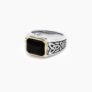 The Mens Sterling Silver and 14K Yellow Gold Onyx Ring, 3.40 TCW features a rectangular black onyx stone in a yellow gold bezel with detailed Celtic knot designs on the sides.