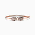The Signature 14K Rose Gold Diamond and Tsavorite Bangle, 0.79 TCW, features two intricately detailed animal heads facing each other with sparkling green tsavorites and diamonds.