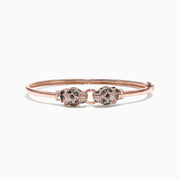 The Signature 14K Rose Gold Diamond and Tsavorite Bangle, 0.79 TCW, features two intricately detailed animal heads facing each other with sparkling green tsavorites and diamonds.