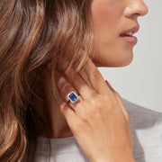 The Nahla Siri 14K White Gold Tanzanite and Diamond Ring, 5.03 TCW, features a large rectangular blue tanzanite center stone surrounded by a halo of baguette and round diamonds in an elegant, intricate design.