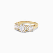 The Bouquet 14K Yellow Gold Three-Stone Diamond Halo Ring, 1.01 TCW, showcases three round diamonds with sparkling halos set in a thick gold band, displayed on a plain white background.