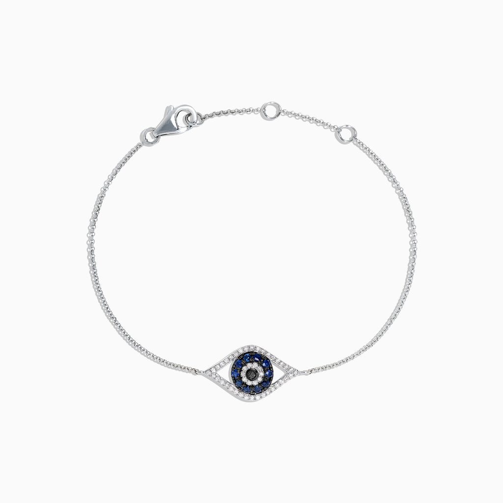 The Novelty 14K White Gold Sapphire & Diamond Evil Eye Bracelet, 0.43 TCW, features a central eye charm set with blue sapphires and diamonds on a fine chain with lobster clasp. Shown on a plain white background.