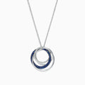 A 14K white gold necklace showcases a pendant of two interlocking circles—one with blue sapphires, the other with diamonds (0.74 TCW)—suspended from a delicate chain on a white background.