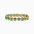 The 14K Yellow Gold Emerald and Diamond Tennis Bracelet showcases oval emeralds framed by diamonds in a classic tennis bracelet design.