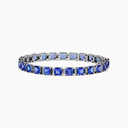 The Nahla Siri 14K White Gold Tanzanite & Diamond Tennis Bracelet, 14.74 TCW, showcases prong-set square-cut tanzanites and diamonds in a sleek row, elegantly displayed on a white background.