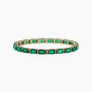 The Brasilica 14K Yellow Gold Emerald & Diamond Tennis Bracelet, 11.76 TCW, features a row of rectangular emeralds in prong settings, accented by diamonds. Elegantly showcased on a white background.