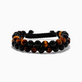 The Mens Tigers Eye Bead Bracelet features alternating glossy black and tiger’s eye brown beads, strung on a black braided adjustable cord. Stylish and versatile, its displayed on a white background—ideal for any occasion.