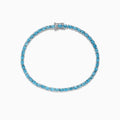 The 925 Sterling Silver Blue Topaz Tennis Bracelet, 9.55 TCW, is shown in a circular shape on a white background, featuring a continuous row of round blue topaz gemstones.