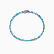 The 925 Sterling Silver Blue Topaz Tennis Bracelet, 9.55 TCW, is shown in a circular shape on a white background, featuring a continuous row of round blue topaz gemstones.