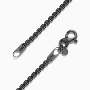 The Mens 925 Sterling Silver Black Rhodium Box Chain Bracelet features a lobster clasp and is displayed in a circular shape on a white background.