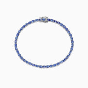 The Nahla Siri Sterling Silver Tanzanite Tennis Bracelet, 6.65 TCW, features oval-cut blue stones in a circular design, set in elegant sterling silver and shown on a white background.