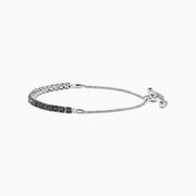 The 14K White Gold Black Diamond Bolo Bracelet features a row of round black diamonds set in a single line, secured with a sliding clasp and accented by two bead ends on the chain.