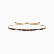 The Watercolors 14K Yellow Gold Tsavorite and Multi Sapphire Tennis Bracelet features closely set vibrant gemstones along an adjustable gold band, showcased on a white background.