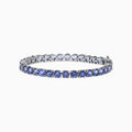 The Nahla Siri Sterling Silver Tanzanite Tennis Bracelet, 15.60 TCW, features a single row of round tanzanite gemstones set in prongs, shown on a white background.