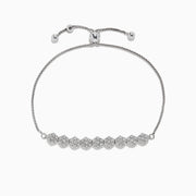 The 925 Sterling Silver Diamond Bolo Bracelet features an adjustable sliding clasp and nine round diamond-studded clusters at the center, totaling 0.22 TCW.