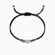 A black cord Novelty 14K White Gold Diamond Heart String Bracelet, 0.13 TCW, with an adjustable sliding knot and a white gold heart charm encrusted with diamonds at the center for sparkling elegance.