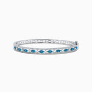 The Bella Bleu 14K White Gold Blue and White Diamond Bangle, 1.27 TCW, features a row of oval blue and white diamonds between two lines of small white crystals, shown on a white background.