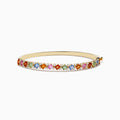 The 14K Yellow Gold Multi Sapphire and Diamond Bangle features a row of multicolored sapphires flanked by diamonds, set across the top against a plain white background.