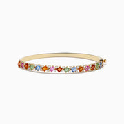The 14K Yellow Gold Multi Sapphire and Diamond Bangle features a row of multicolored sapphires flanked by diamonds, set across the top against a plain white background.