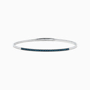 The Bella Bleu 14K White Gold Blue Diamond Bangle showcases a slim white gold design accented with brilliant blue diamonds, offering an elegant sparkle to any ensemble.