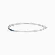 The Bella Bleu 14K White Gold Blue Diamond Bangle showcases a slim white gold design accented with brilliant blue diamonds, offering an elegant sparkle to any ensemble.