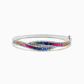The 14K White Gold Multi Sapphire and Diamond Bangle showcases wavy rows of pink, blue, green, orange, and clear gemstones in an intricate and sparkling pattern for a vibrant look.