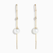 The 14K Yellow Gold Pearl and Diamond Drop Earrings feature a single white pearl and round diamond on each, accented with thin gold chains and bars.