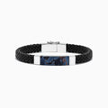 The Mens Sterling Silver Pietersite Woven Leather Bracelet, 12.50 TCW, features black woven leather, a sterling silver clasp, and a rectangular silver accent with a dark blue pietersite marbled center, shown on a white background.