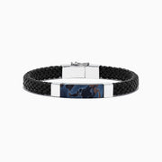 The Mens Sterling Silver Pietersite Woven Leather Bracelet, 12.50 TCW, features black woven leather, a sterling silver clasp, and a rectangular silver accent with a dark blue pietersite marbled center, shown on a white background.
