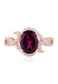 The Bordeaux 14K Rose Gold Rhodolite Garnet and Diamond Ring, 3.11 TCW, showcases a striking oval rhodolite garnet at its center with swirling diamond-accented bands—an exquisite choice for any occasion.