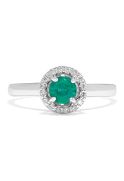 The Brasilica 14K White Gold Emerald and Diamond Halo Ring, 0.60 TCW, features a round green emerald centered in a halo of sparkling white diamonds, presented against a white background.