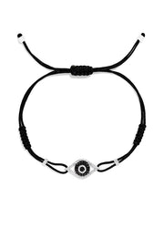 The Novelty White Gold Black & White Diamond Evil Eye Bracelet, 0.43 TCW, features an eye-shaped charm with a central black stone and clear accents on a black adjustable cord with sliding knots for easy sizing.