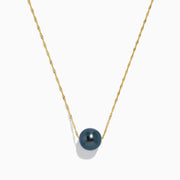 The 14K Yellow Gold Tahitian Pearl Necklace features a twisted gold chain and a single round black pearl centerpiece, elegantly displayed against a white background.