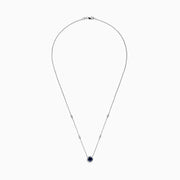 The Royale Bleu 14K White Gold Sapphire and Diamond Necklace, 1.11 TCW, features a round blue sapphire pendant with a halo of clear stones and two diamonds set along each side of the chain.