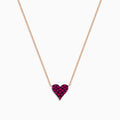 The 14K Rose Gold Ruby Pave Heart Necklace features a heart-shaped pendant encrusted with sparkling rubies on a delicate rose gold chain, displayed against a plain white background.