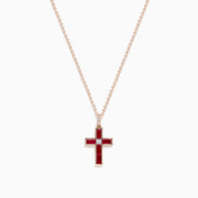 The Ruby Royale 14K Rose Gold Ruby and Diamond Cross Pendant, featuring a small clear center stone, is displayed on a rose gold chain against a white background.