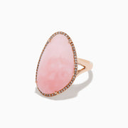 The 14K Rose Gold Pink Opal and Diamond Ring showcases a large, asymmetrical pink opal accented with small diamonds on a simple rose gold band, displayed against a white background.