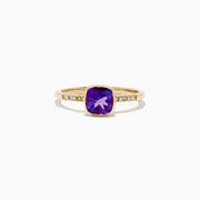 The 14K Yellow Gold Amethyst and Diamond Ring, 0.75 TCW features a cushion-cut amethyst center accented by round diamonds set into the band on each side.